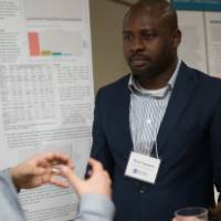 Students listen to a poster presentation
